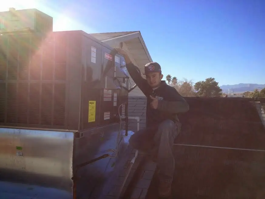 HVAC technician performing Air Duct Repair on a rooftop unit in New Kingman-Butler